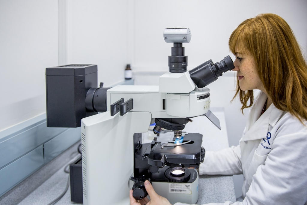 Hand holding a container with yellowish liquid