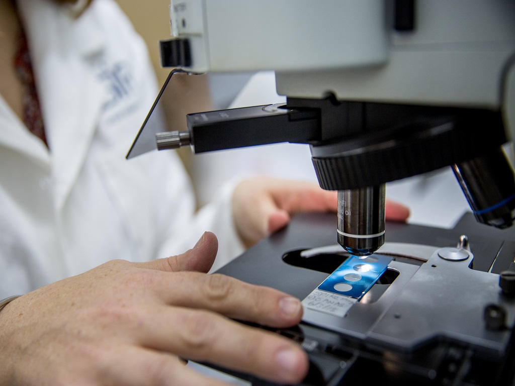 Hand holding a container with yellowish liquid