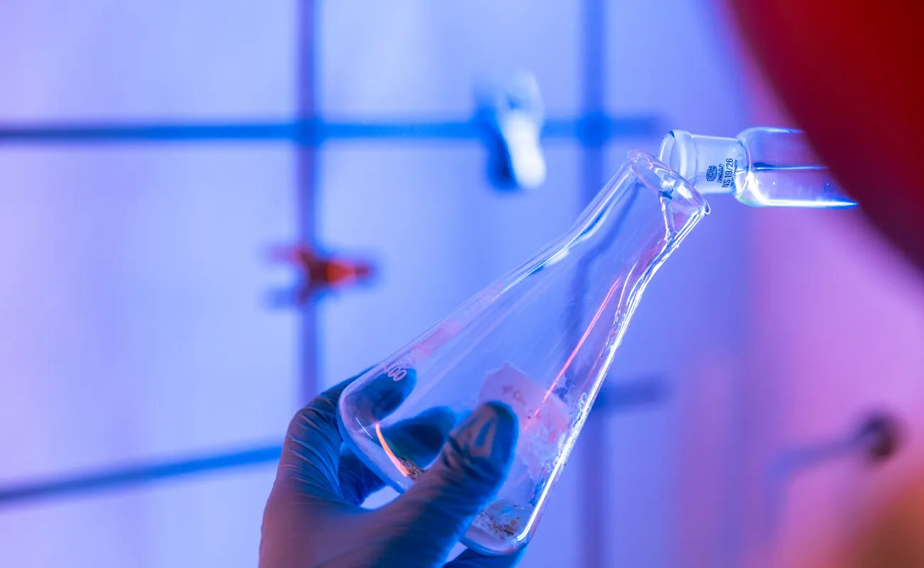 person pouring liquid into a beaker